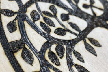 closeup of a tree of life burned on wood