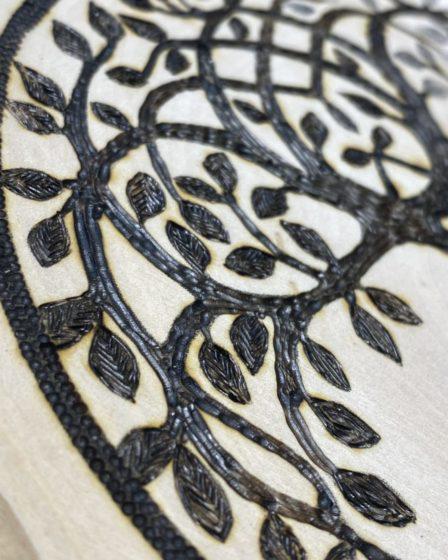 closeup of a tree of life burned on wood
