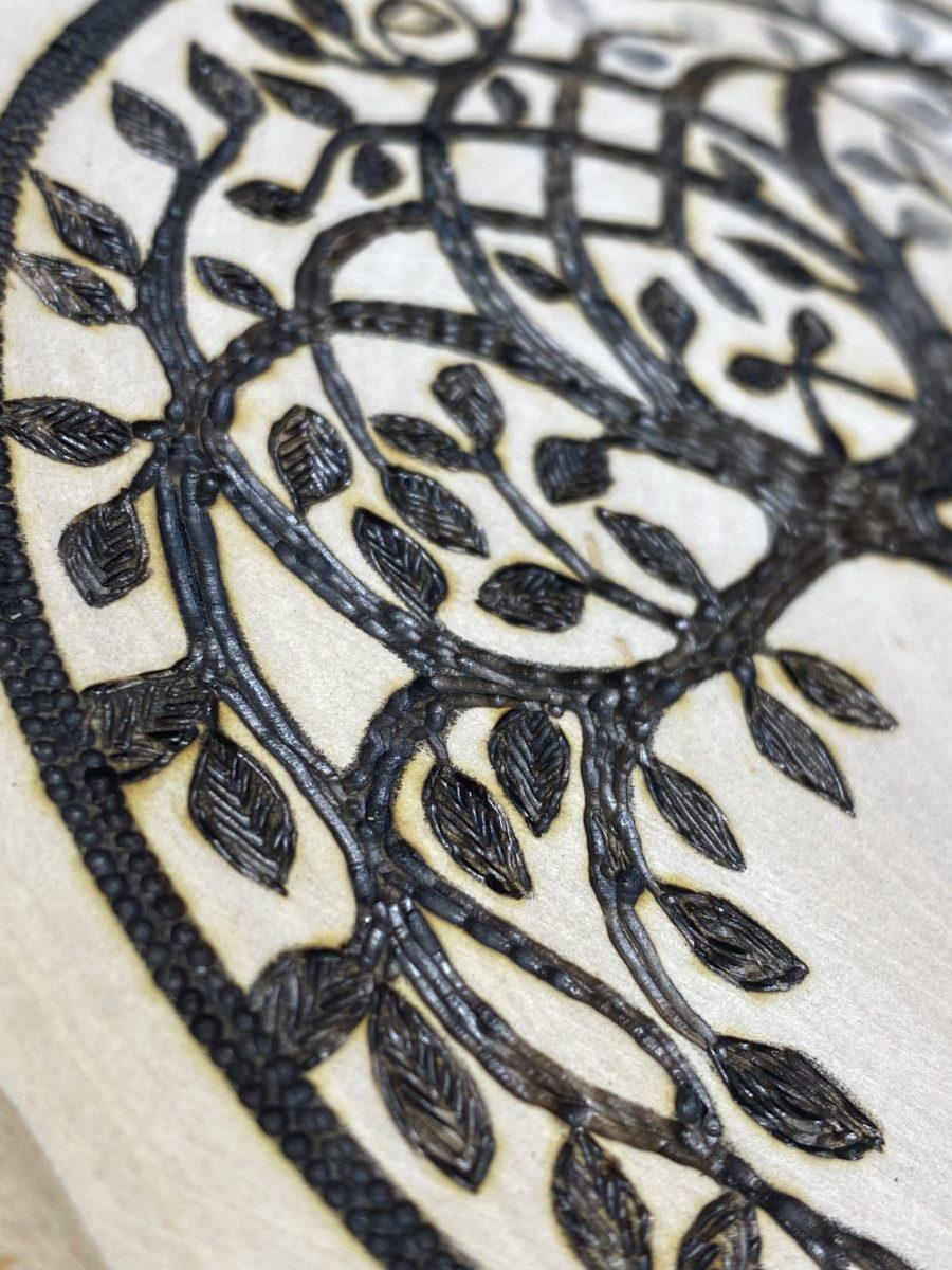 closeup of a tree of life burned on wood