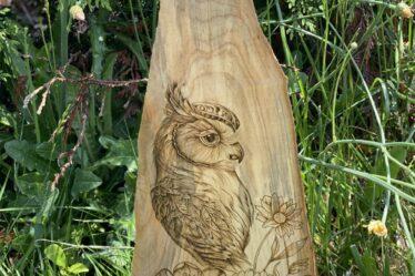 An owl and floral arrangement burned on wood