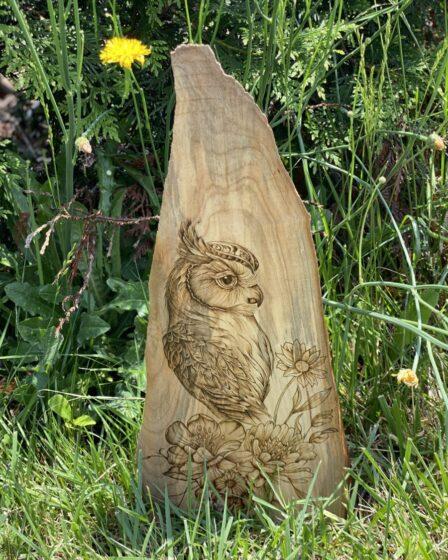 An owl and floral arrangement burned on wood