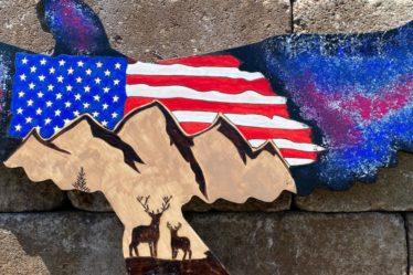An American flag and nature scene burned on eagle shaped wood