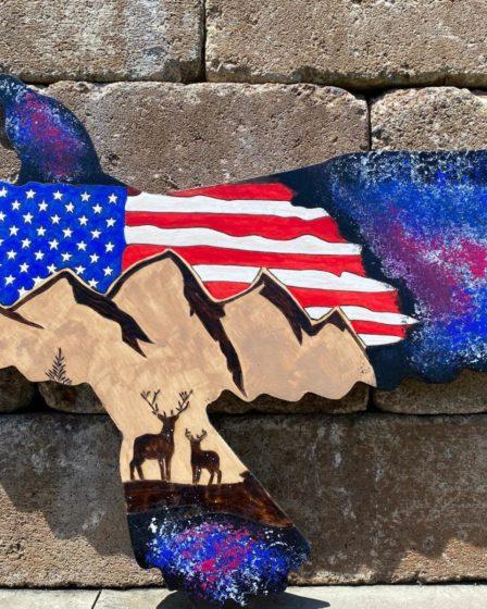 An American flag and nature scene burned on eagle shaped wood