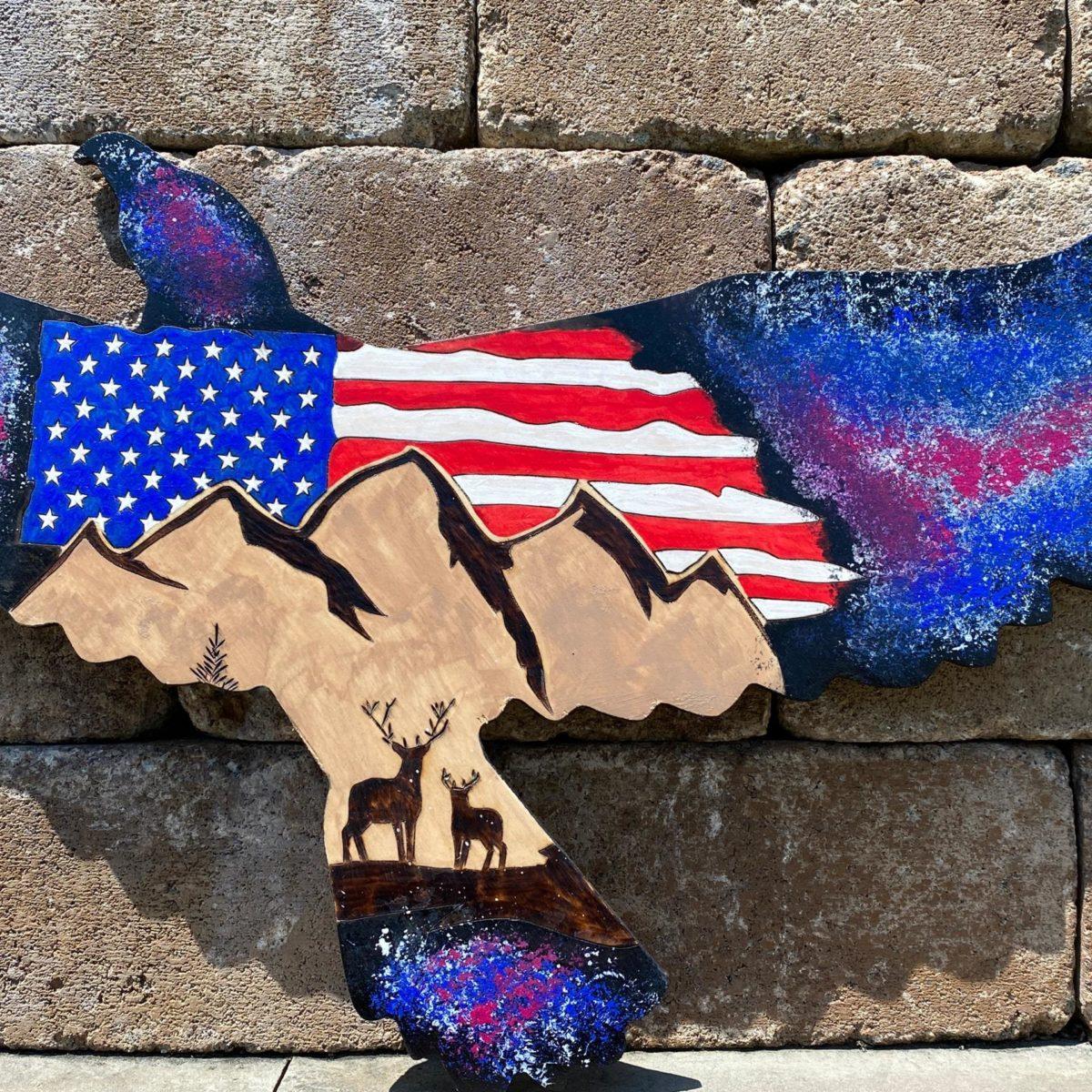 An American flag and nature scene burned on eagle shaped wood